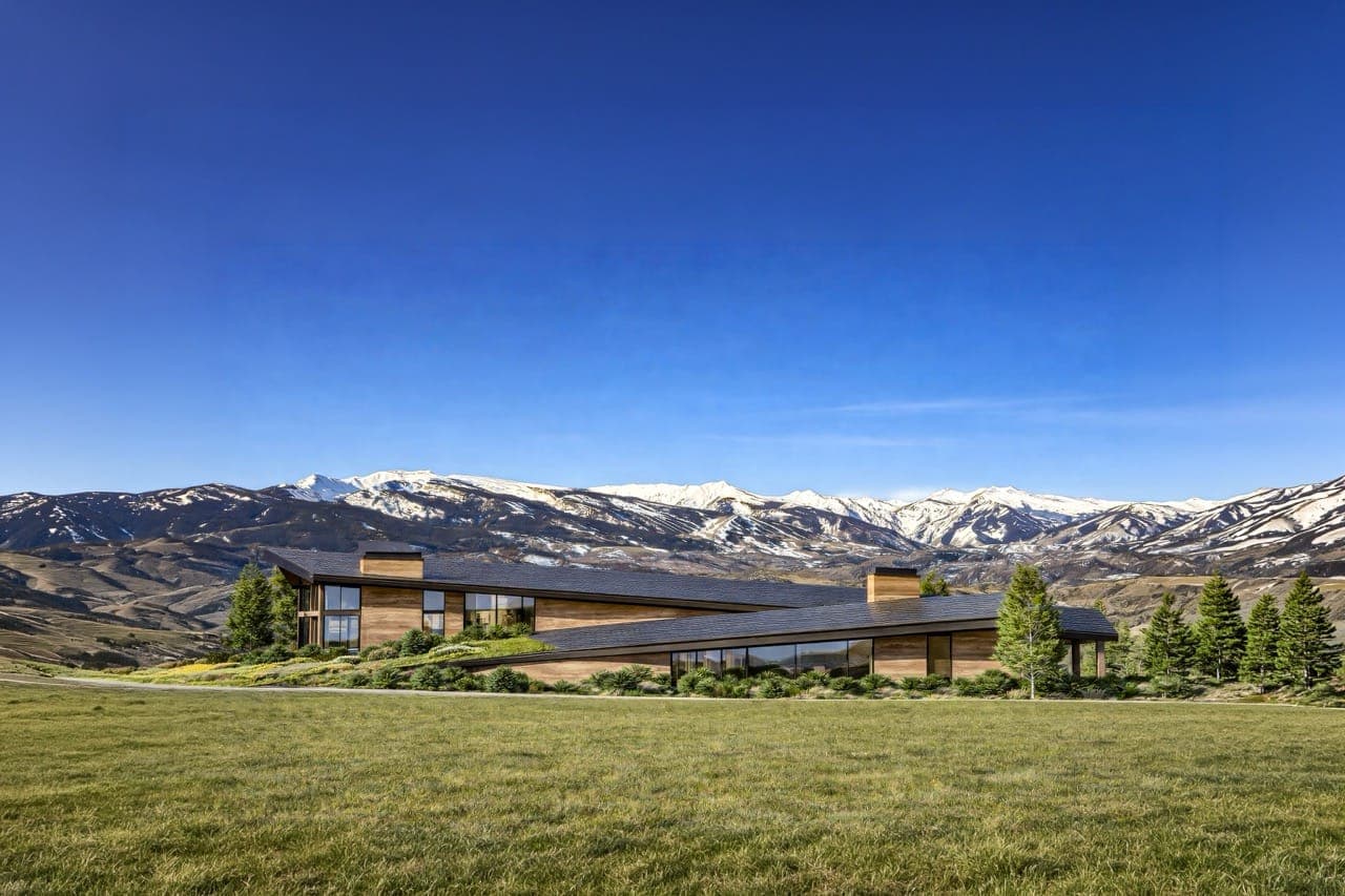 Low timber-and-glass building settled into the mountain landscape