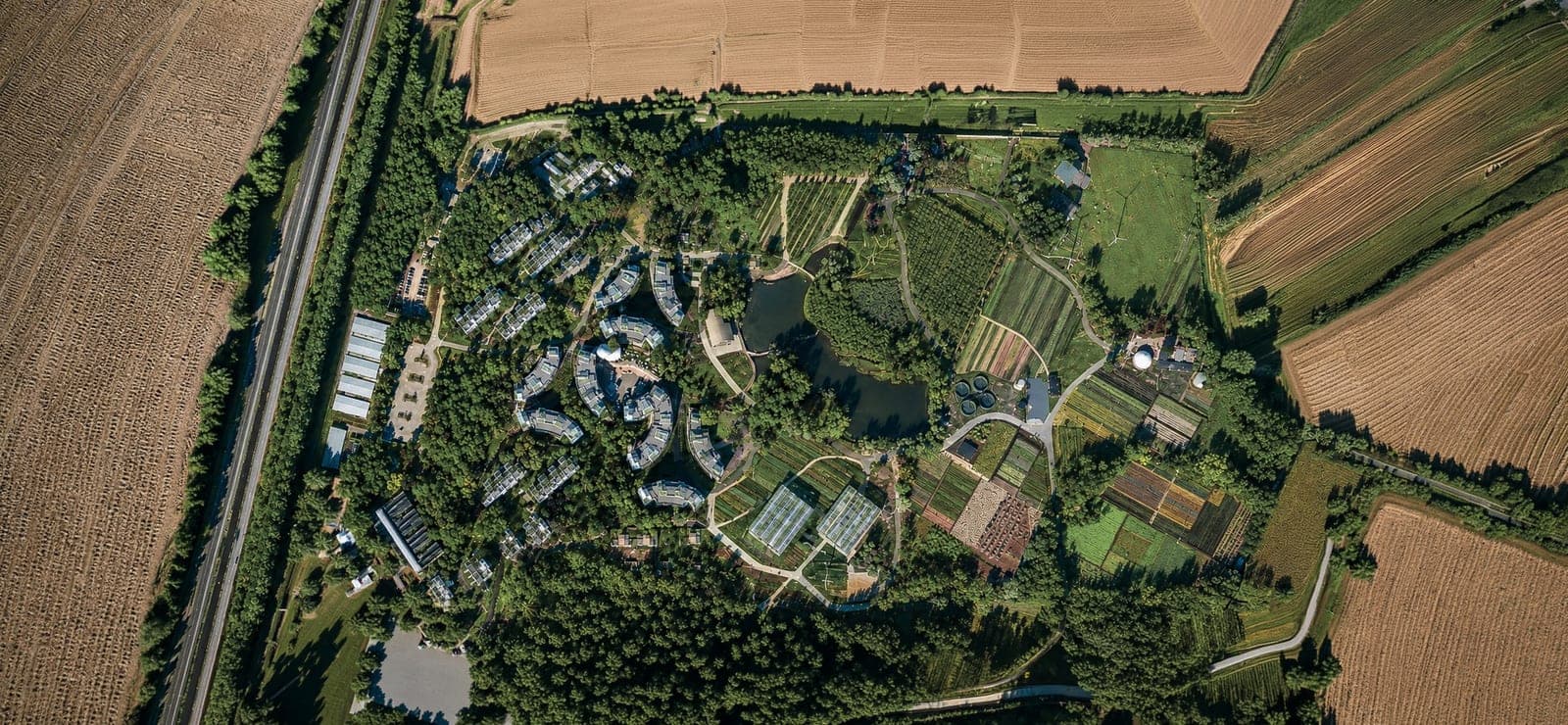 Aerial view of an eco-village with solar-roofed homes, ponds and market gardens
